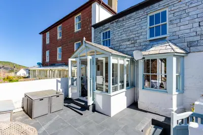 a patio with a conservatory in front of a brick building at Luxury Fisherman’s Cottage Historic Port Isaac in Port Isaac