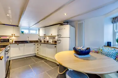 a kitchen with a table and a refrigerator at Luxury Fisherman’s Cottage Historic Port Isaac in Port Isaac