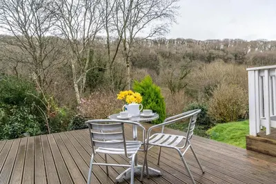 a table and two chairs on a wooden deck at Lower Hill Cottage w/Swedish Hot Tub in Bodmin