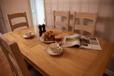 a wooden table with a book and a plate of food at Lower Hill Cottage w/Swedish Hot Tub in Bodmin