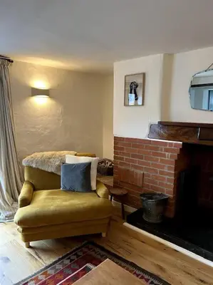 a living room with a chair and a fireplace at Bay Tree Barn in Truro