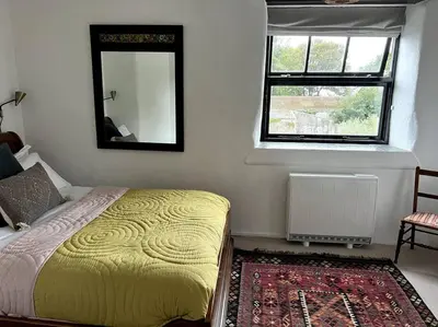 a bedroom with a bed and a mirror and a window at Bay Tree Barn in Truro