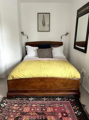 a bedroom with a bed with yellow sheets and a rug at Bay Tree Barn in Truro