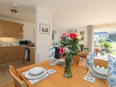 a dining room with a table with a vase of flowers at Foxglove Cottage in Falmouth