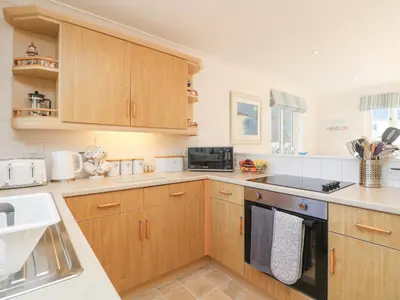 a kitchen with wooden cabinets and a stove top oven at Foxglove Cottage in Falmouth