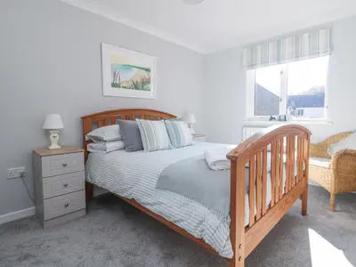 a bedroom with a wooden bed and a window at Foxglove Cottage in Falmouth
