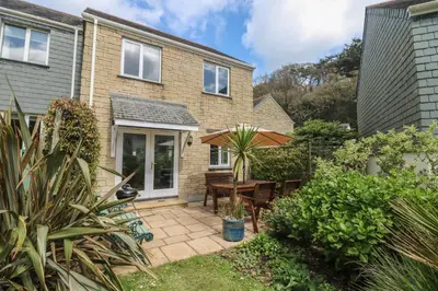 a garden with a patio and a house at Foxglove Cottage in Falmouth