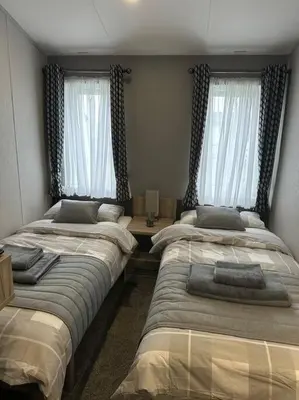 a bedroom with two beds and two windows at Modern Lodge with Amazing Views in Newquay