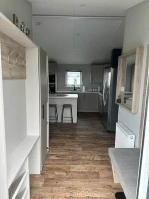 a kitchen with white cabinets and a wooden floor at Modern Lodge with Amazing Views in Newquay