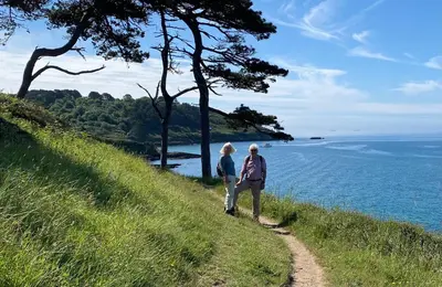 two people walking on a hill overlooking the ocean at 5 SEAVIEW private parking w EV in Saint Mawes