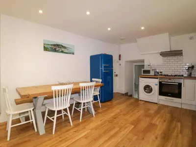 a kitchen with a table and chairs and a blue refrigerator at Sun Cottage in Looe
