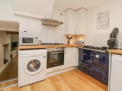 a kitchen with a washing machine and a microwave at Sun Cottage in Looe