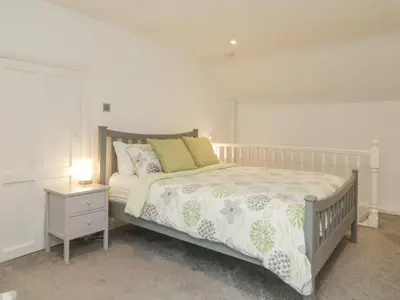 a bedroom with a bed and a night stand with a lamp at Sun Cottage in Looe