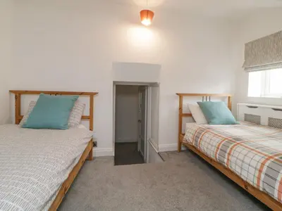 a bedroom with two beds and a window at Sun Cottage in Looe