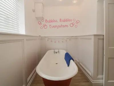 a bathroom with a white sink and a sign on the wall at Sun Cottage in Looe