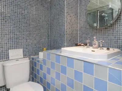 a bathroom with a sink and a toilet and a mirror at Sun Cottage in Looe