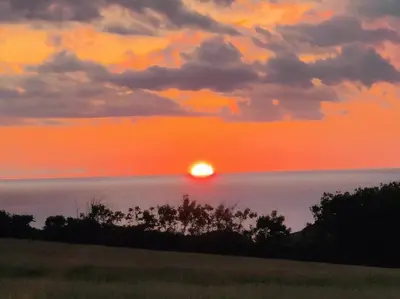a sunset over the ocean with the sun in the sky at Little Swelle Cabin with awesome Sea views in Poundstock