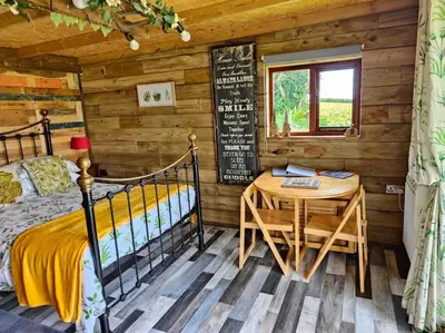 a bedroom with a bed and a table in a log cabin at Little Swelle Cabin with awesome Sea views in Poundstock