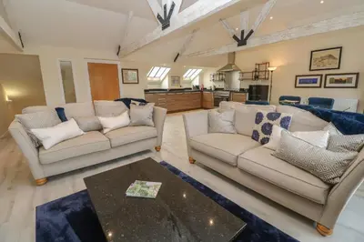 a living room with two couches and a table at The Penthouse in Helston