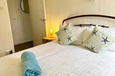 a white bed with pillows and a towel on it at Nook Cottage Seaside Charm & Countryside Calm in Newquay