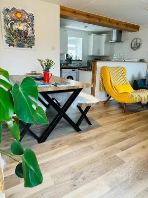 a dining room with a table and a yellow chair at Nook Cottage Seaside Charm & Countryside Calm in Newquay