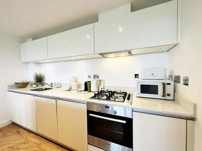 a kitchen with white cabinets and a stove and microwave at 24 Zinc in Newquay