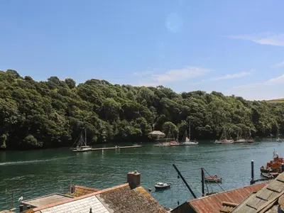 a river with boats docked in the water with trees at 21 Passage Street formerly Panacea in Fowey