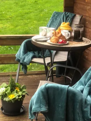 a table with a plate of food on a porch at Polgwedhen Lodge in Truro