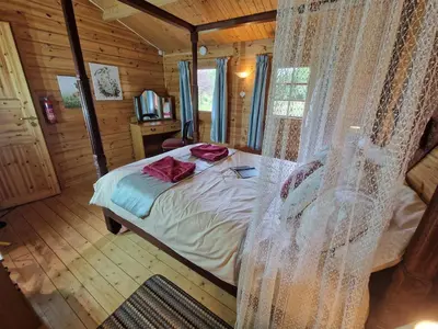 a bedroom with a bed in a wooden cabin at Polgwedhen Lodge in Truro