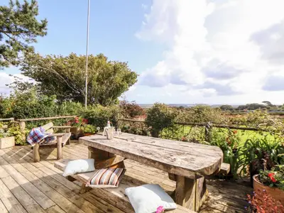 a wooden deck with a wooden table and chairs at Little Roskrow in Penryn