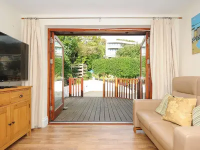 a living room with a couch and a sliding glass door at Little Trevallan in Looe