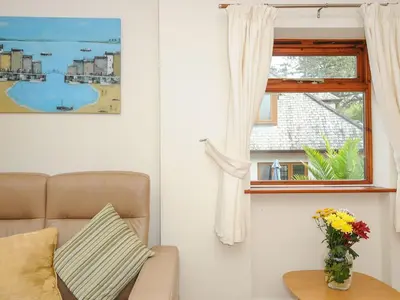 a living room with a couch and a window at Little Trevallan in Looe