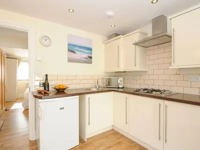 a kitchen with white cabinets and a counter top at Little Trevallan in Looe