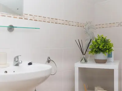 a white bathroom with a sink and a plant at 5 St Brigids in St Ives
