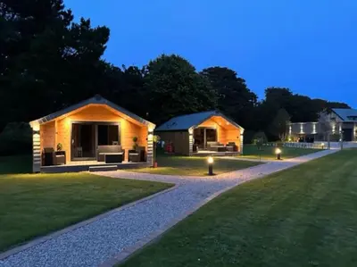 a house with lights on the lawn at night at Riverside Retreats - Steamers Meadow in Gwinear
