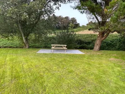 a picnic table in the middle of a grass field at Riverside Retreats - Steamers Meadow in Gwinear