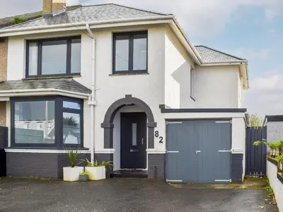 a white house with a blue garage at Eighty Two in Newquay