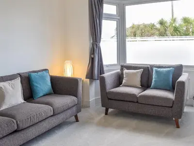 a living room with two chairs and a couch and a window at Eighty Two in Newquay