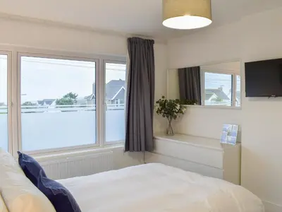 a bedroom with a bed and two windows at Eighty Two in Newquay