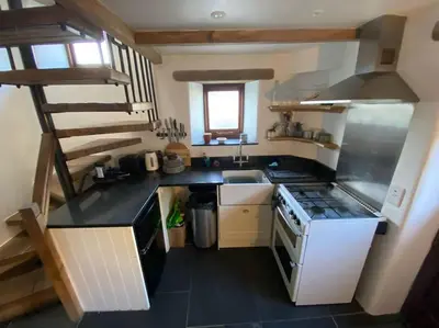 a small kitchen with a stove and a sink at 9A Viaduct Cottage - the cosiest bolthole in the SW! in Hayle