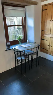 a table and chairs in a room with a window at 9A Viaduct Cottage - the cosiest bolthole in the SW! in Hayle