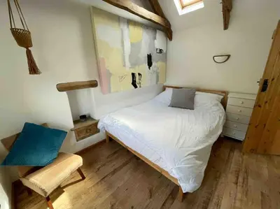 a small bedroom with a bed and a chair at 9A Viaduct Cottage - the cosiest bolthole in the SW! in Hayle