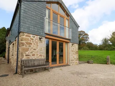 a stone house with a bench in front of it at The Orchard in Bodmin