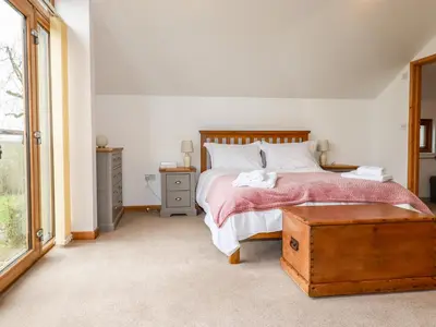 a bedroom with a large bed and a window at The Orchard in Bodmin