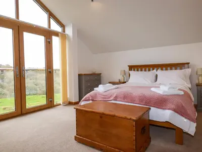 a bedroom with a bed and a large window at The Orchard in Bodmin