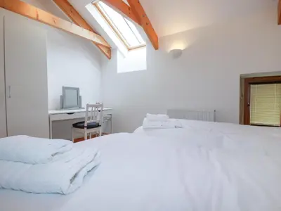 a bedroom with a white bed with a desk and a window at The Orchard in Bodmin