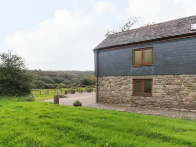 a stone house with a green yard next to a field at The Orchard in Bodmin
