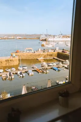 a window with a view of a marina with boats at Breathtaking Harbourside Views With Parking at 'Harbour Strand' in Falmouth