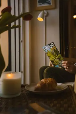a person reading a book next to a plate of food at Breathtaking Harbourside Views With Parking at 'Harbour Strand' in Falmouth