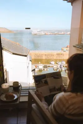 a woman sitting in a chair looking out at the water at Breathtaking Harbourside Views With Parking at 'Harbour Strand' in Falmouth